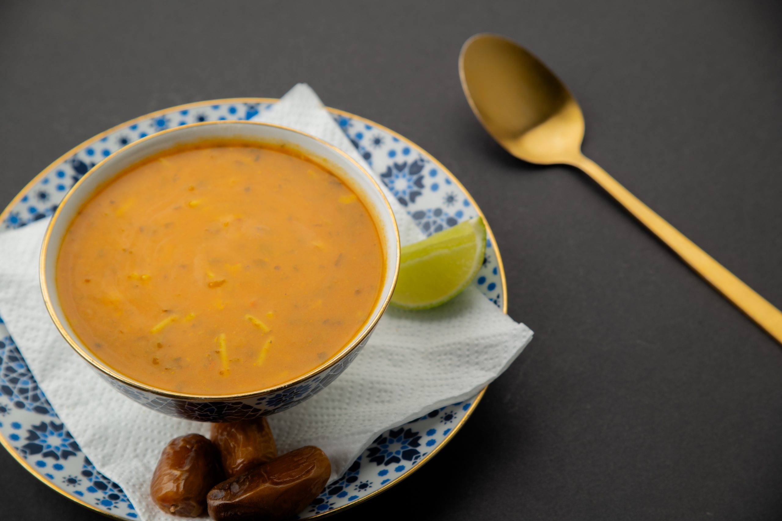 a bowl of soup with a spoon and dates on a plate